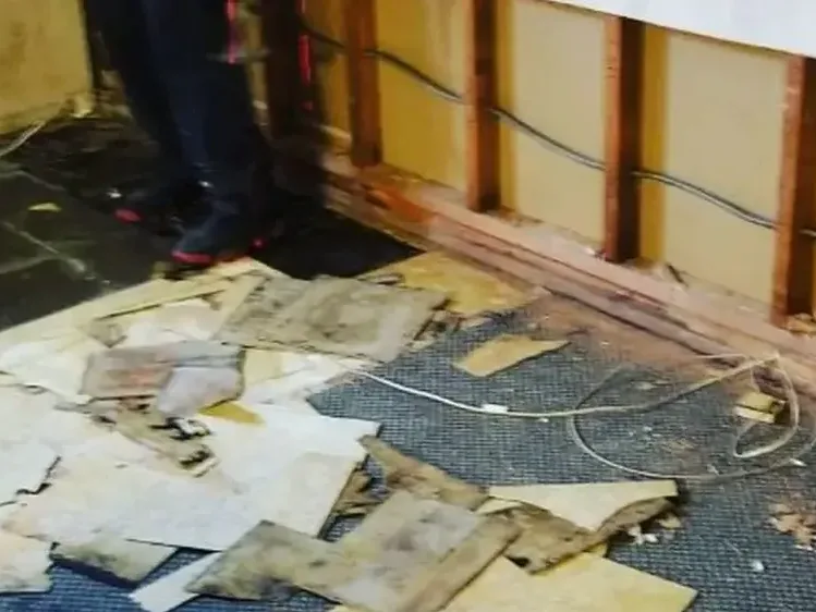 Exposed lower wall framing beside damaged flooring and removed finish material