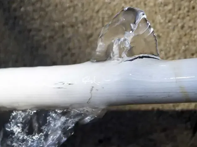 Water spraying out of a split in a plastic supply pipe