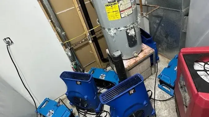 Air movers and a dehumidifier positioned in a water heater closet