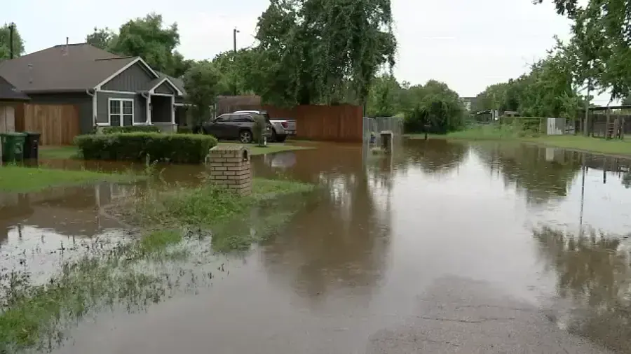 Floodwater across a residential street and the front yards of homes