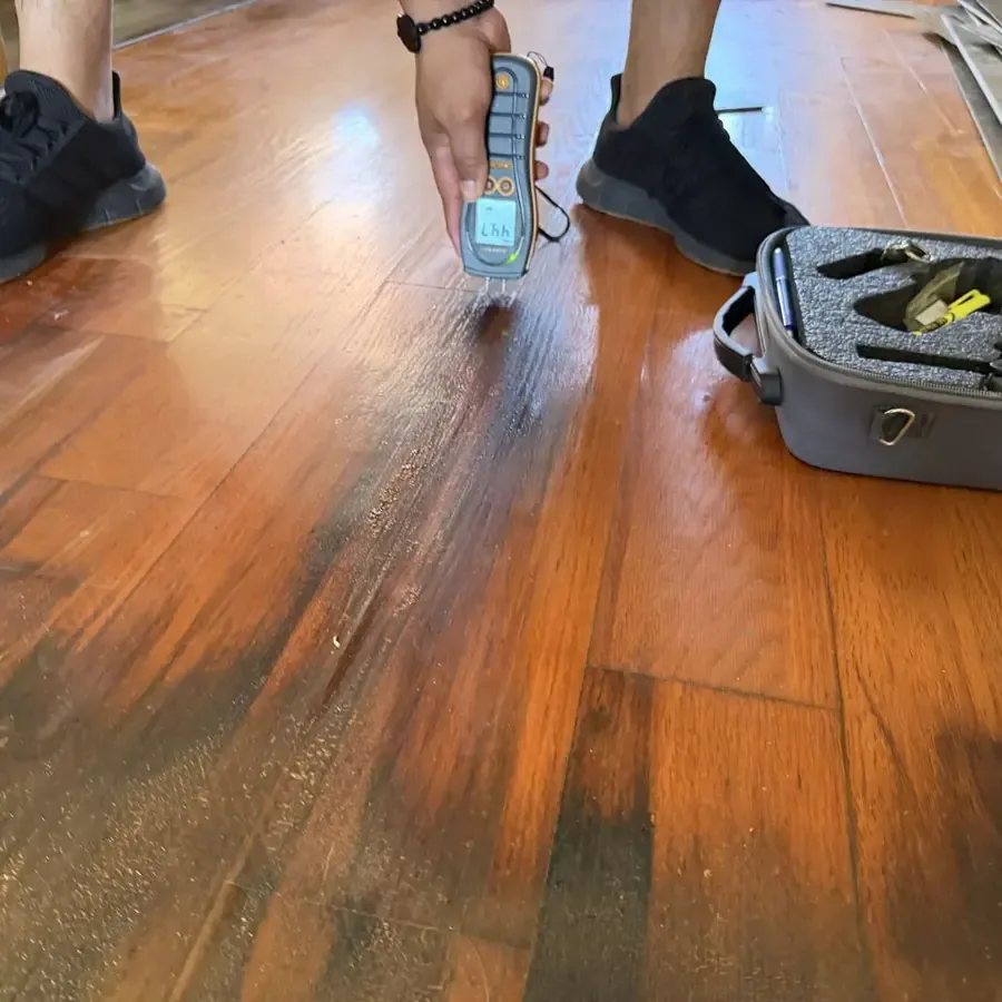 A moisture meter checking the surface of a hardwood floor