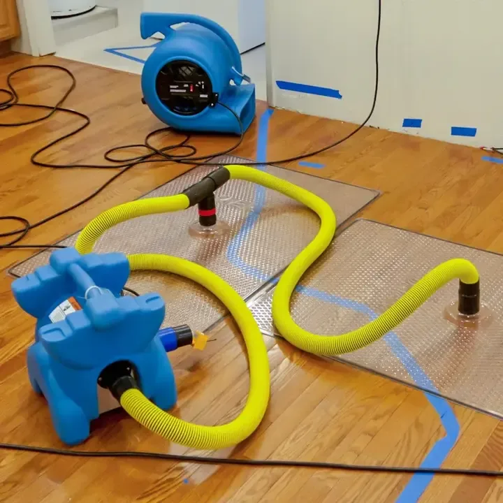 Blue air movers and drying mats connected by yellow hoses